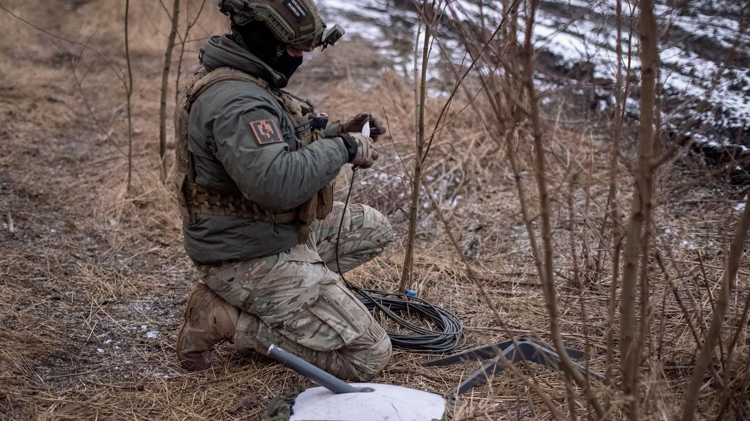 Image caption,A Ukrainian soldier using a Starlink satellite internet terminal which connects to thousands of SpaceX satellites