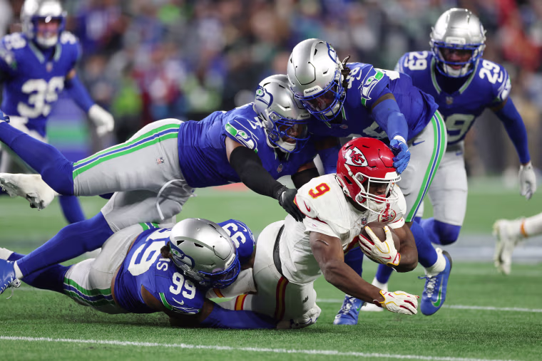 Chiefs running back Kenneth Walker III is tackled by Leonard Williams, Uchenna Nwosu and Tyrice Knight of the Seahawks.Caleb Bowlin / Getty Images