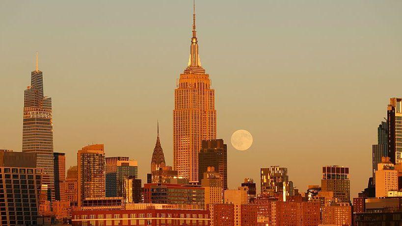 Image caption,An autumn glow as the Hunter's Moon rises behind the skyline of midtown Manhattan in New York City, US