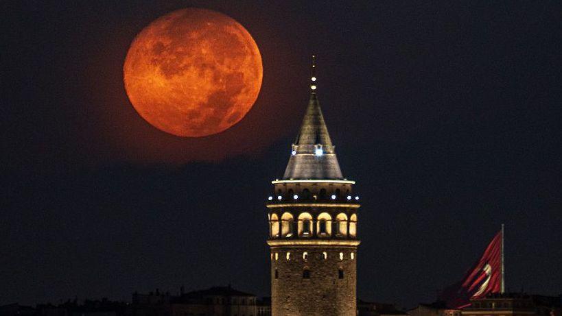 Image caption,The full moon glowing a beautiful burnt orange over the Galata Tower in Istanbul, Turkey