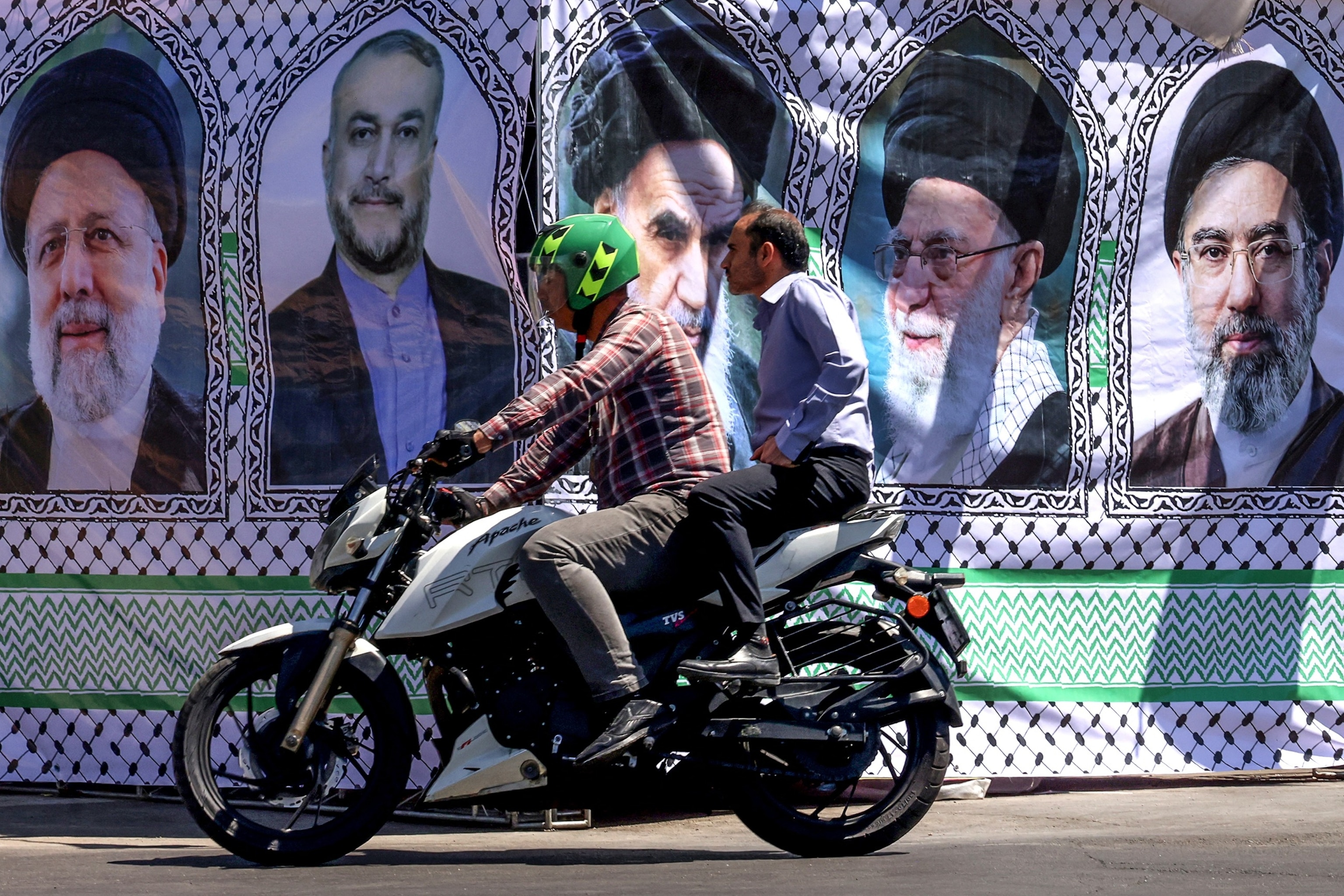 A man rides his motorbike past a banner depicting Iranian leaders in Tehran on May 25, 2026.Atta Kenare/AFP via Getty Images