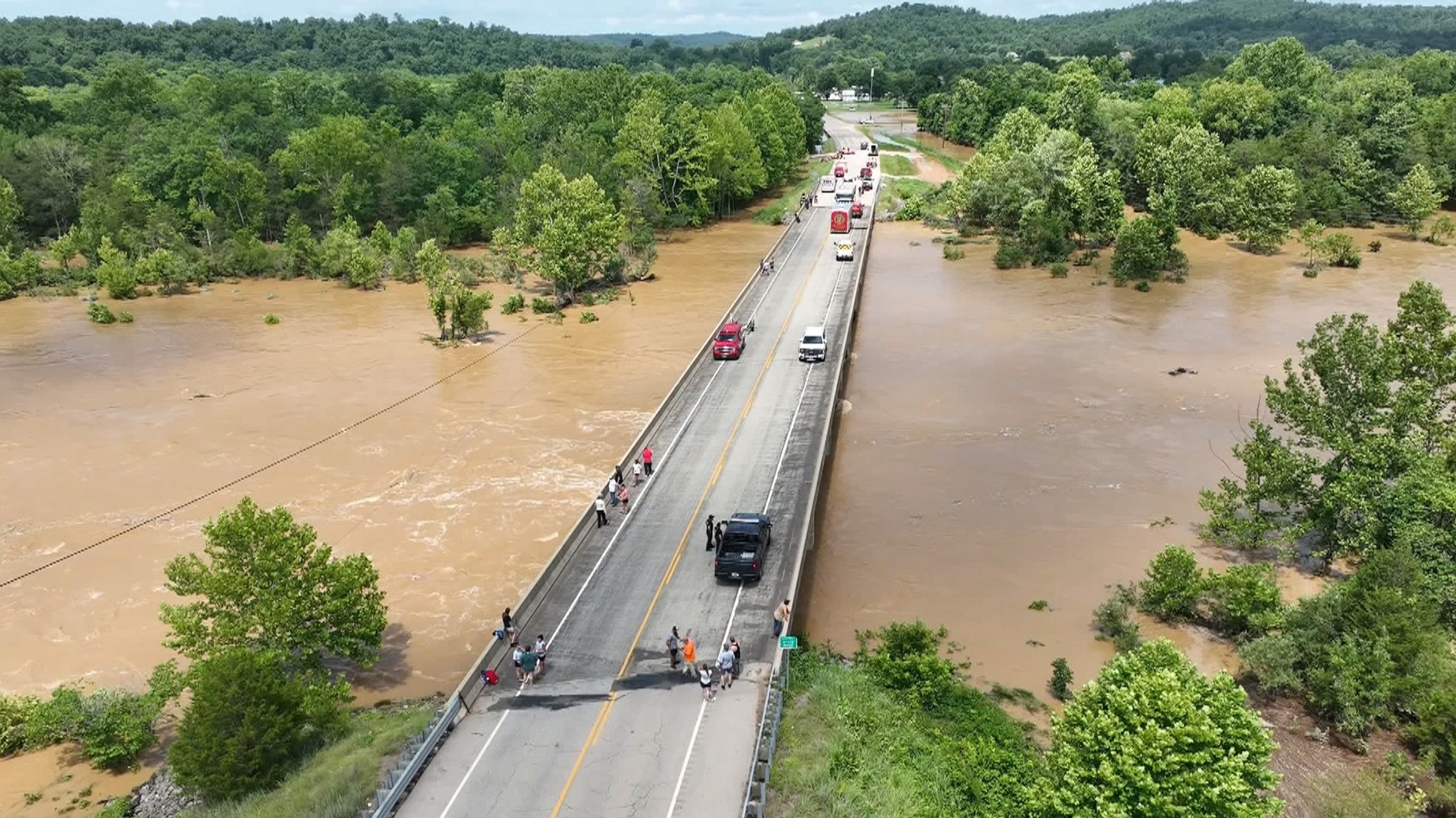 People stand on a bridge above the floodwaters of the Black River in Lesterville, Missouri, July 10, 2026.Heartland News