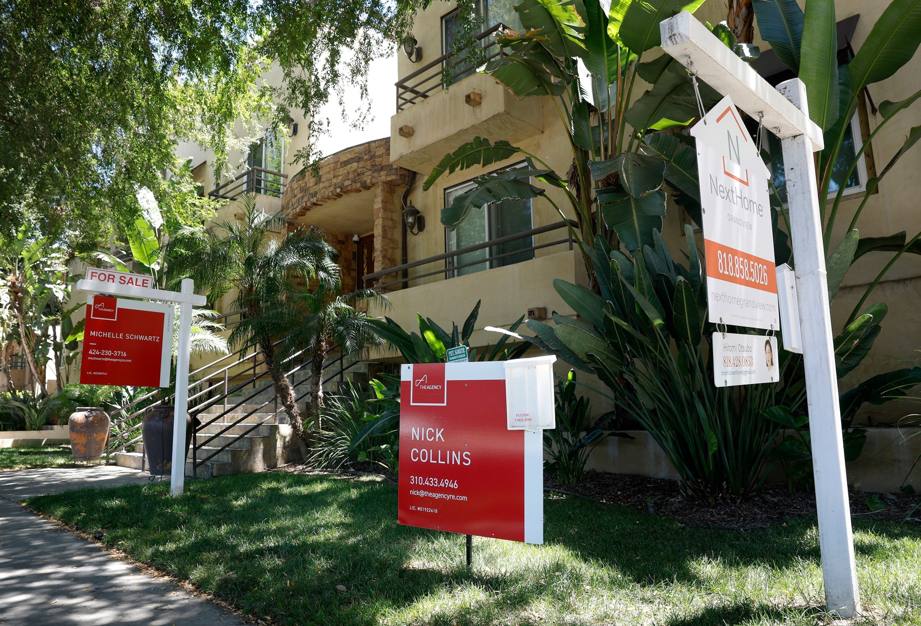 "For Sale" sign in a grass yard in front of a large house.STOCK PHOTO/Adobe Stock