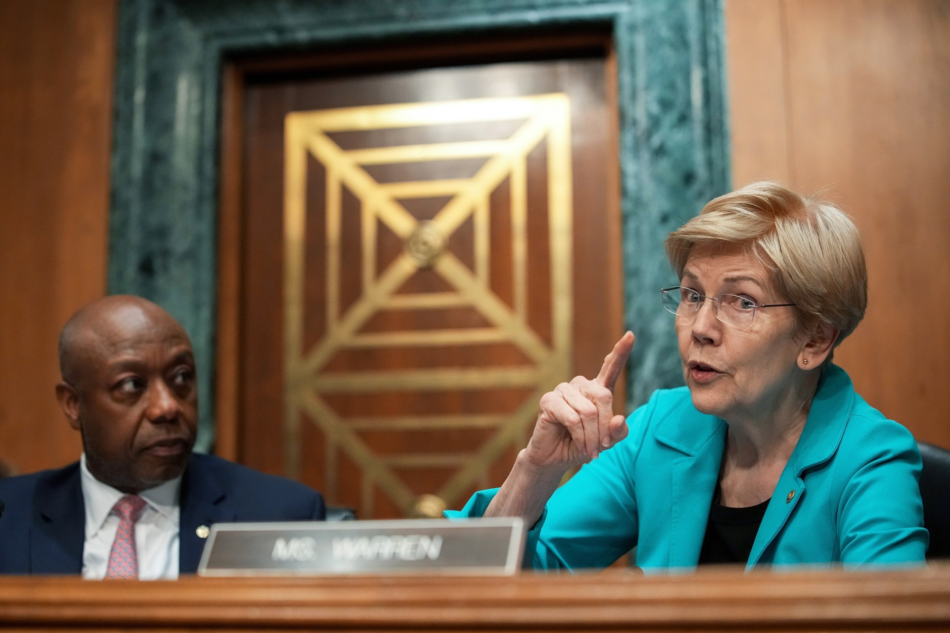 In this April 21, 2026, file photo, Committee Chairman Sen. Tim Scott looks on as ranking member Sen. Elizabeth Warren (D-MA) speaks during a Senate Committee on Banking, Housing, and Urban Affairs confirmation hearing for Kevin Warsh, in Washington, D.C.Andrew Harnik/Getty Images, FILE