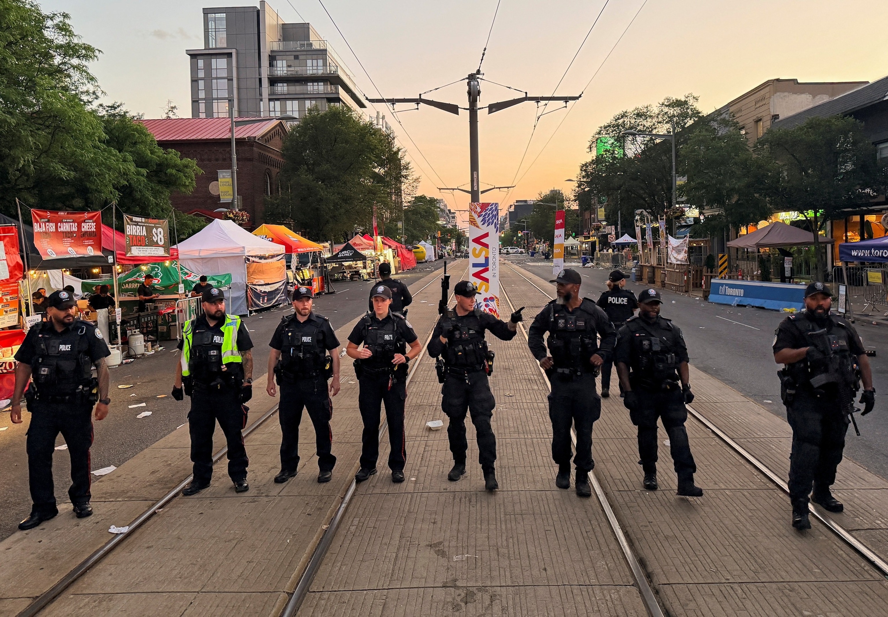 Police officers stand guard at the site of a deadly shooting at a salsa-themed street festival in Toronto, Ontario, Canada, July 11, 2026. Picture taken using a mobile phone.Cole Burston/Reuters