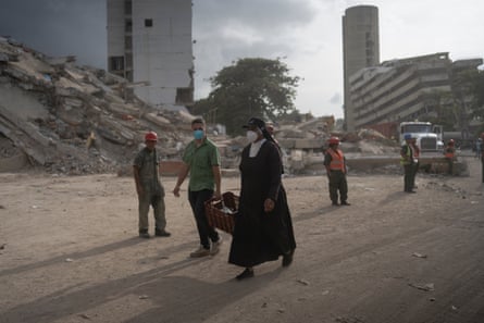 A nun walks in front of the wreckage of the OPPE 33 building in La Guaira.