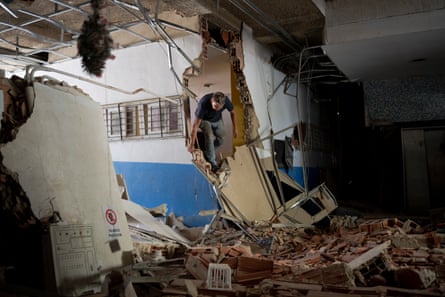 A man walks over the rubble inside the remains of the OPPE 25 complex In La Guaira.