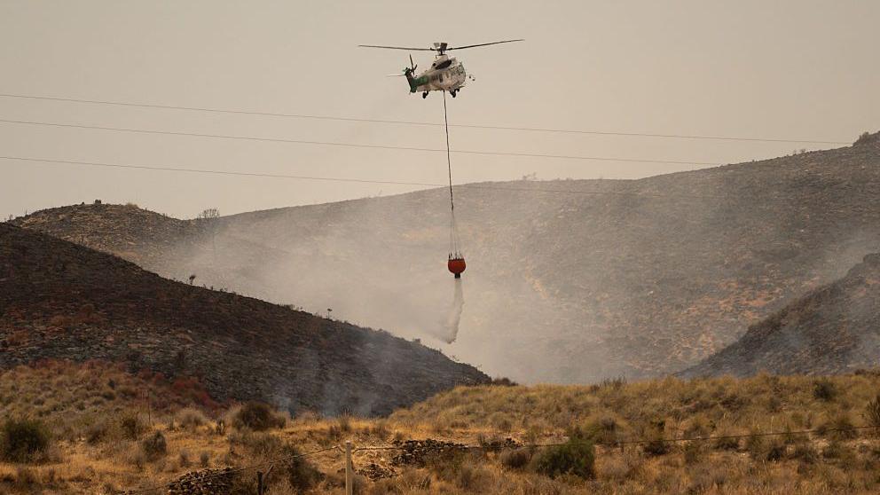 Image caption,An Andalusia Wildfire Service helicopter damping down embers on Saturday