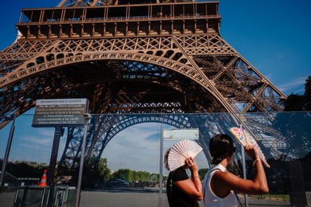 Tourists walk past the Eiffel Tower, where a sign announces its early closure on Saturday.Photograph: Dimitar Dilkoff/AFP/Getty Images