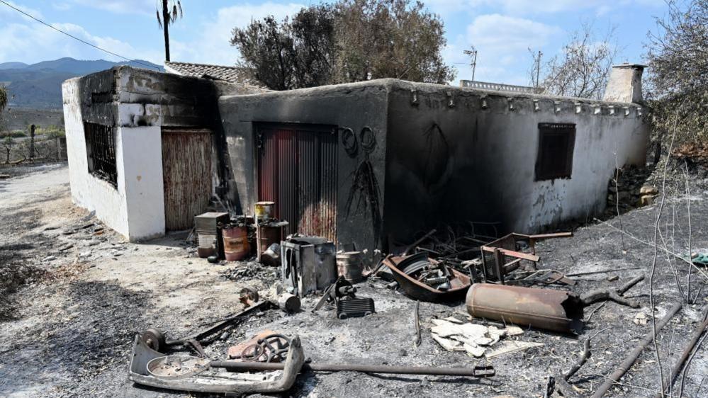 Image caption,The charred ruins of a restaurant in Bédar, destroyed by Thursday's wildfire
