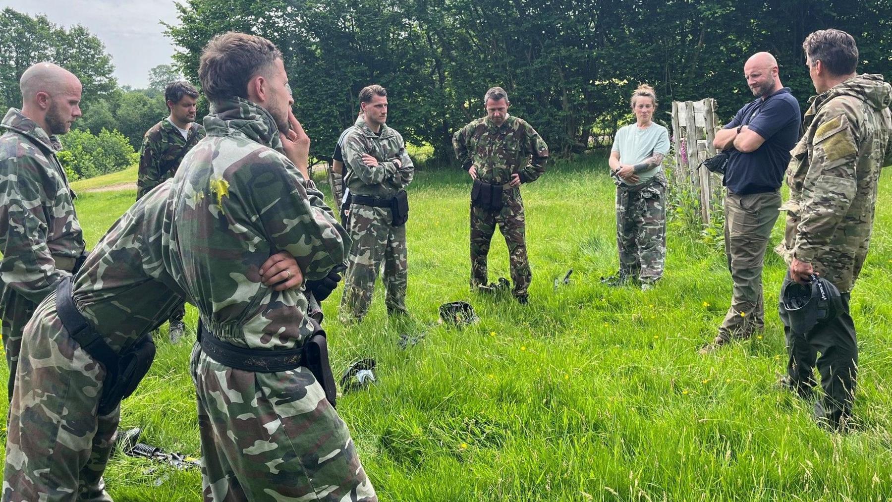 Image caption,A group including Michael Bradley (left), Piet Cremers (fourth left) and Ella Masar (third right) listen to feedback after an ambush exercise