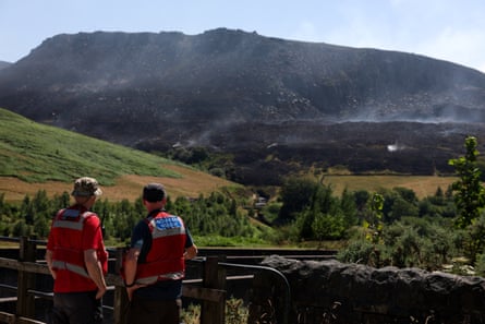 Emergency services members look at smoke rising from a moorland blaze, near the Dovestone Reservoir, in Manchester.Photograph: Temilade Adelaja/Reuters