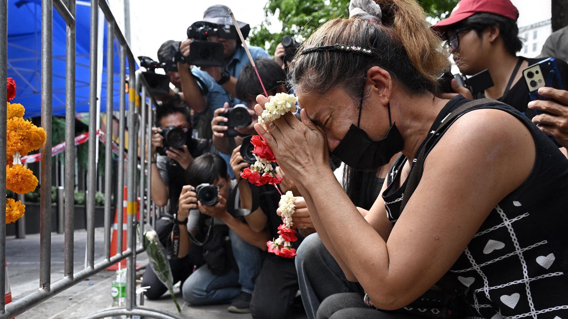 Image caption,A woman prays for her deceased daughter and her son-in-law