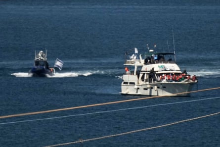 Activists in orange life jackets sit on a flotilla boat, intercepted while approaching the Gaza coast, as Israeli navy soldiers sail it into the port of Ashdod.Photograph: Léo Corrêa/AP