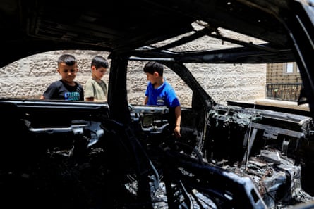 Children gather near a damaged car, said to have been burned by Israeli settlers, near Hebron in the West Bank.Photograph: Mussa Qawasma/Reuters