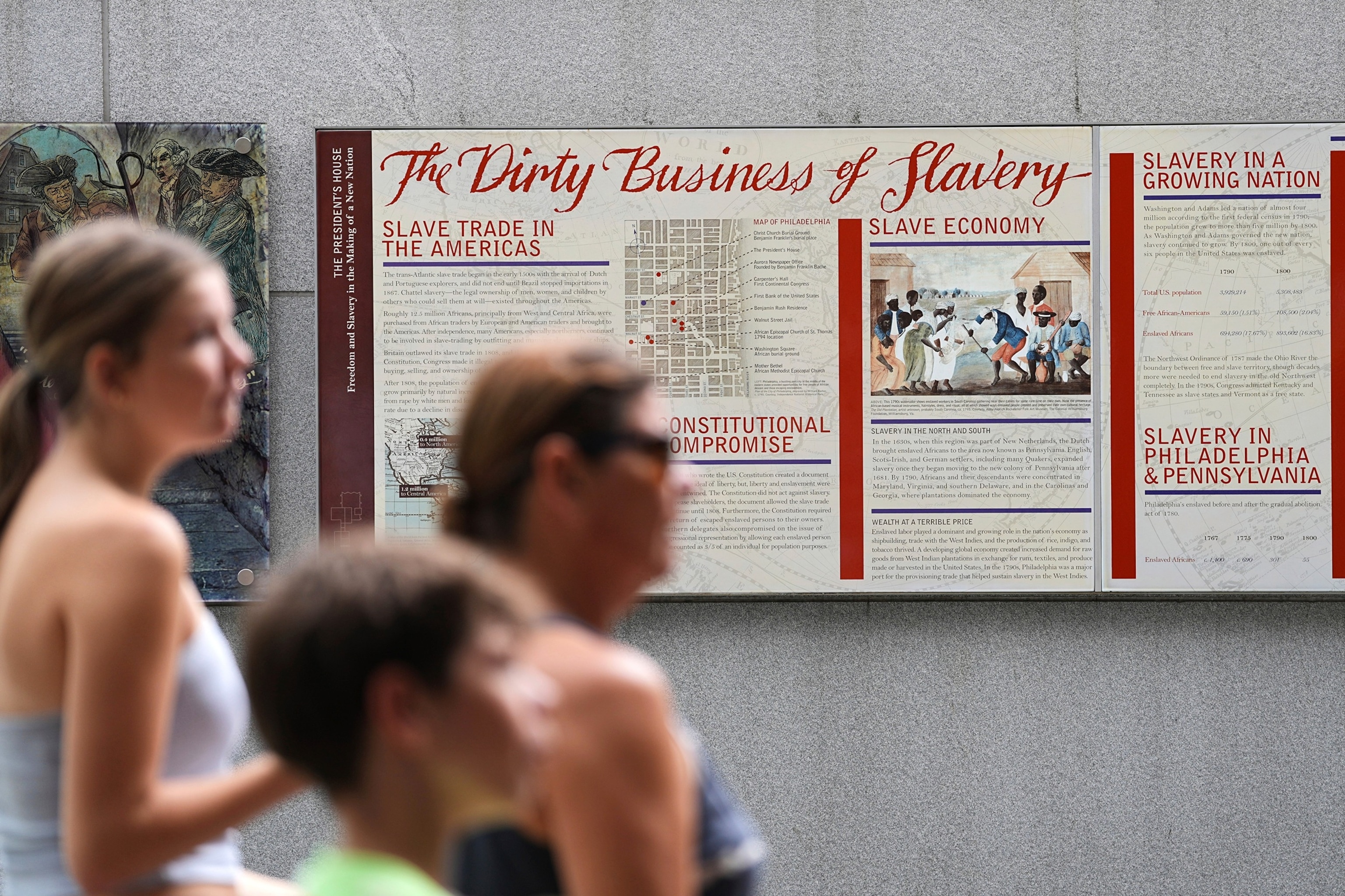 In this Aug. 19, 2025, file photo people walk past an informational panel at President's House Site in Philadelphia.Matt Rourke/AP, FILE