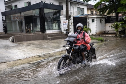 A motorcyclist rides along a flooded street in Lagos, Nigeria, on 30 June.Photograph: Olympia de Maismont/AFP/Getty