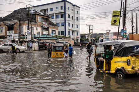 Pedestrians wade through a flooded street in Lagos on 3 July.Photograph: Olympia de Maismont/AFP/Getty