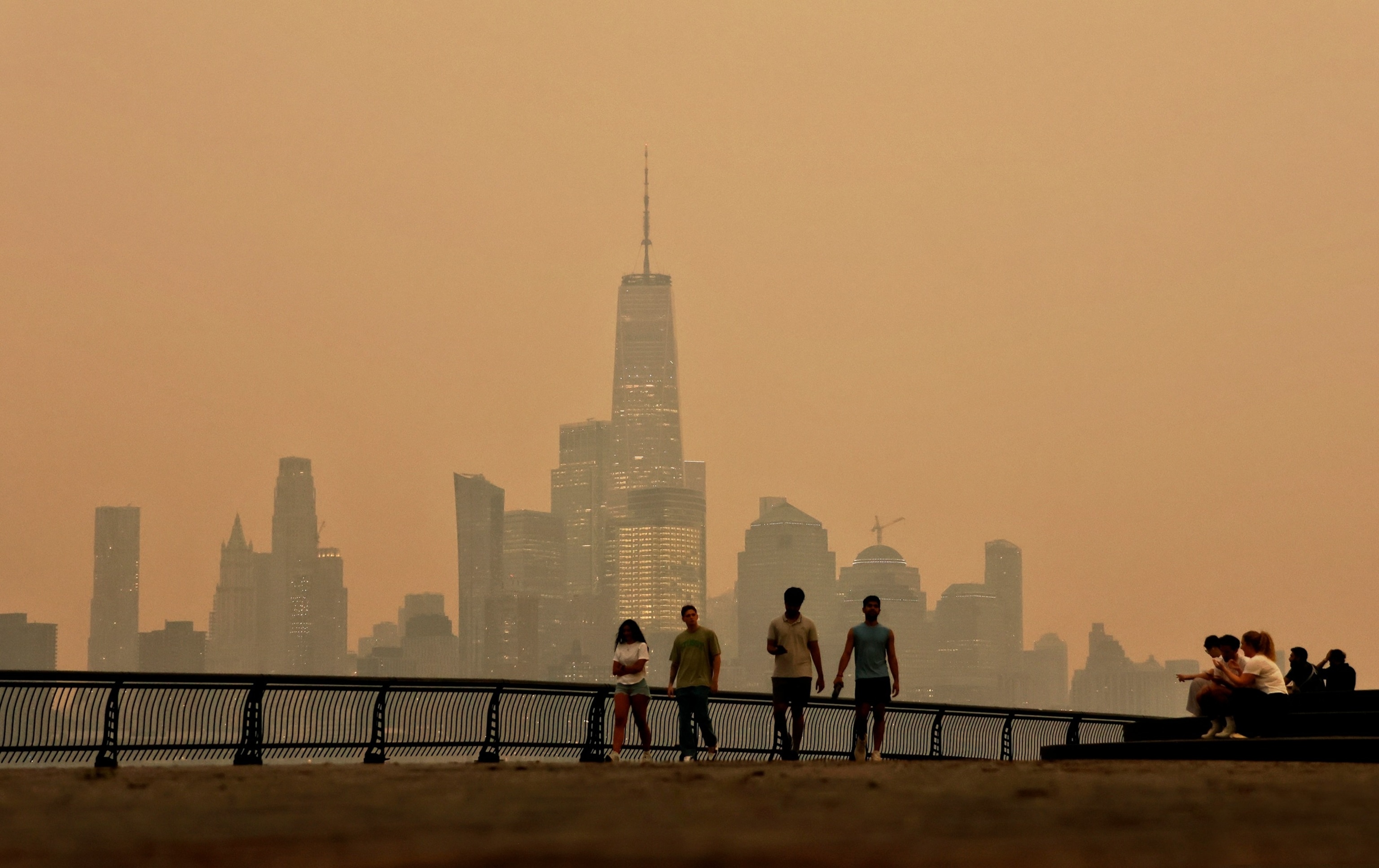 A person wearing a face mask walks near the Brooklyn Bridge as wildfire smoke from Canada causes hazy conditions on July 16, 2026, in New York.Angela Weiss/AFP via Getty Images