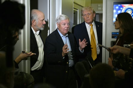 Lindsey Graham flanked by Donald Trump and the secretary of commerce, Howard Lutnick, speaks with reporters aboard Air Force One on their way back to Washington DC on 4 January 2026.Photograph: Jim Watson/AFP/Getty Images