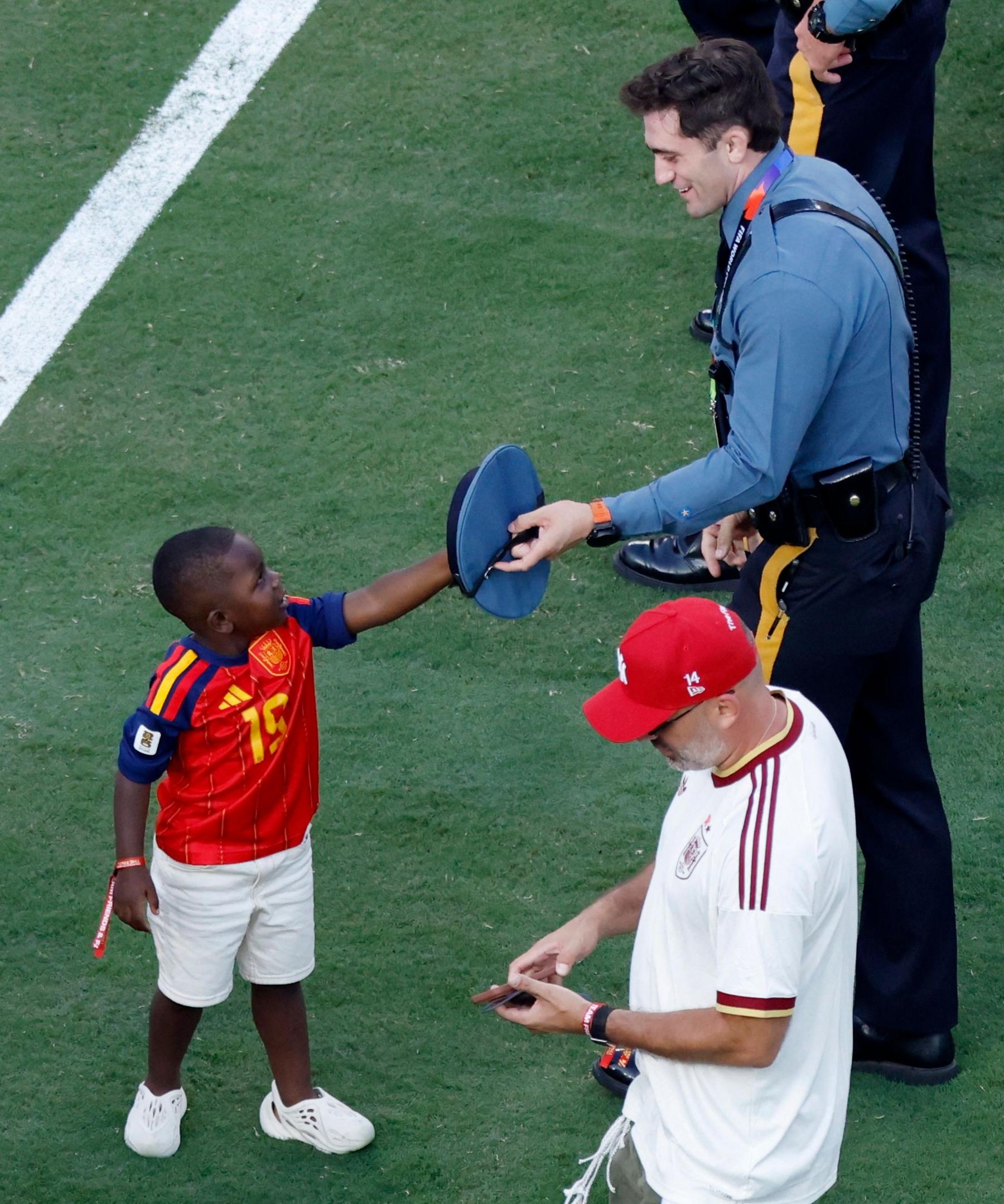 Image caption,Kenye smiles as he is handed a hat by a policeman