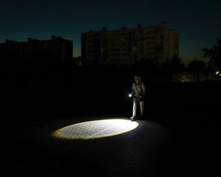 A pedestrian in Yevpatoria uses a torch after authorities limited electricity supplies.Photograph: Alexey Pavlishak/Reuters