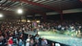 A performer dances on stage and tosses beer to the crowd during a concert at Gooch Sports Arena
