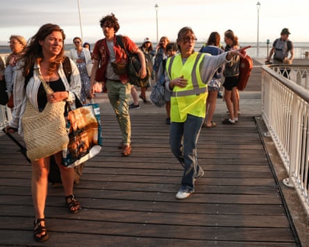 A volunteer guides holidaymakers evacuated from Cap Ferret after they arrive by boat in Arcachon.Photograph: Romain Perrocheau/AFP/Getty
