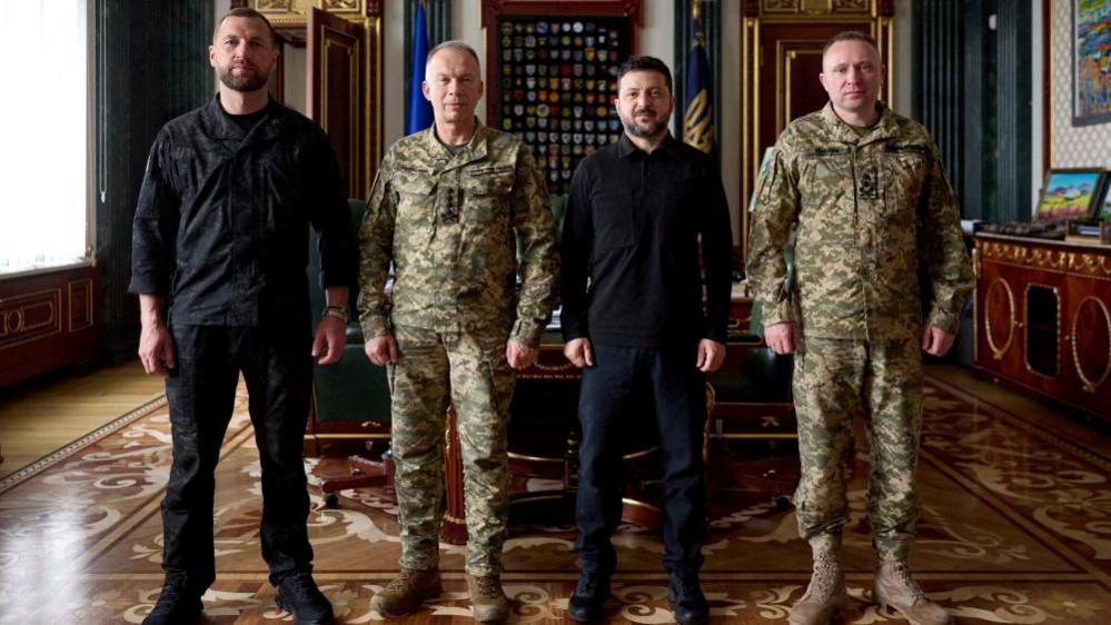Image caption,Zelensky (C-R) sought to present a united front this week, standing beside Mykhailo Drapatyi (R), his predecessor and the acting defence minister (L)