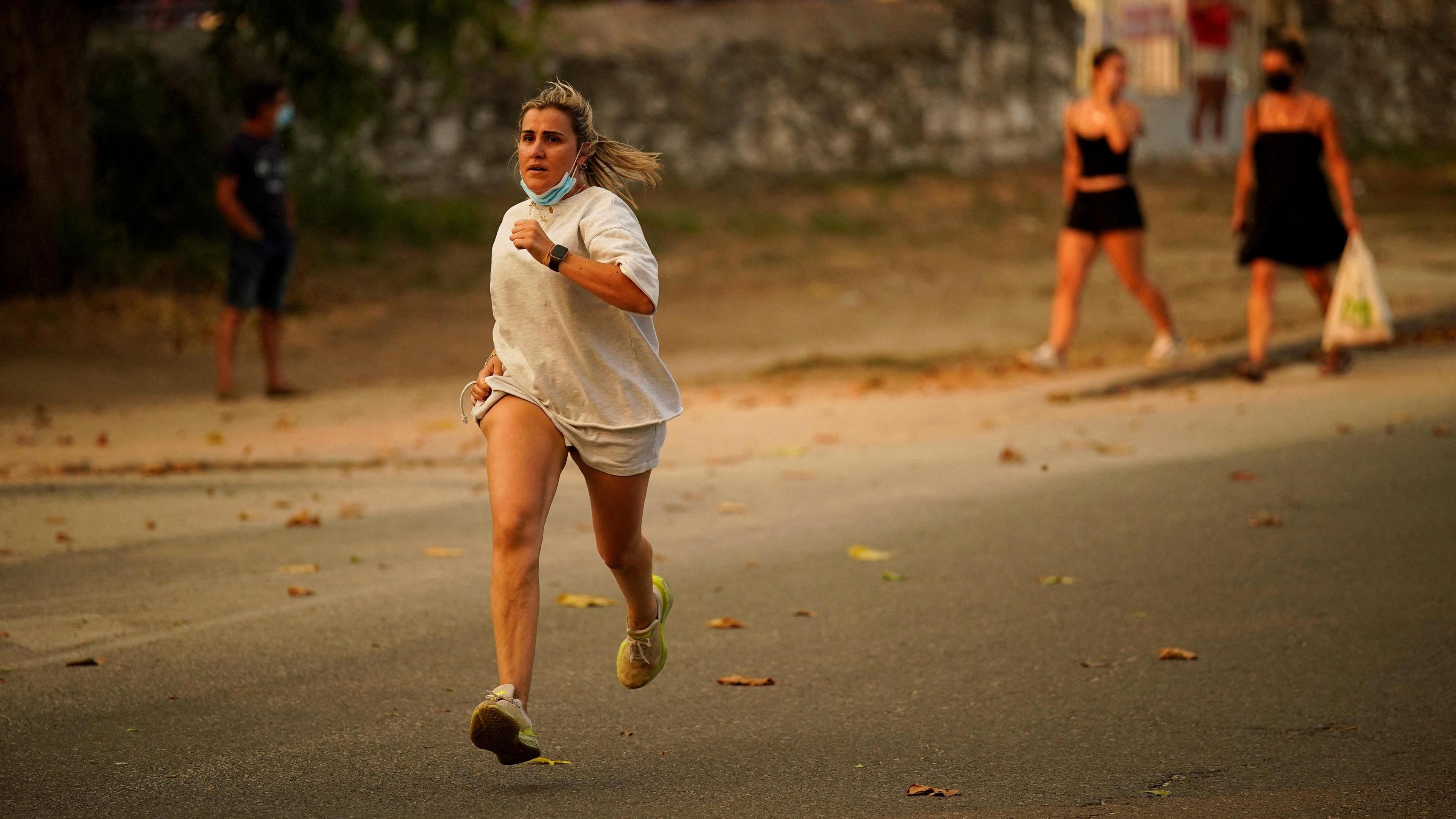 Image caption,A woman runs as a wildfire spreads through Avila province in Spain