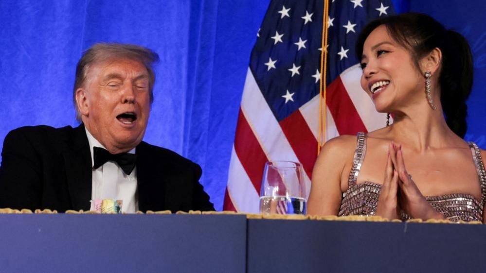 Image caption,Trump laughs at the dinner, alongside WHCA President Weijia Jiang