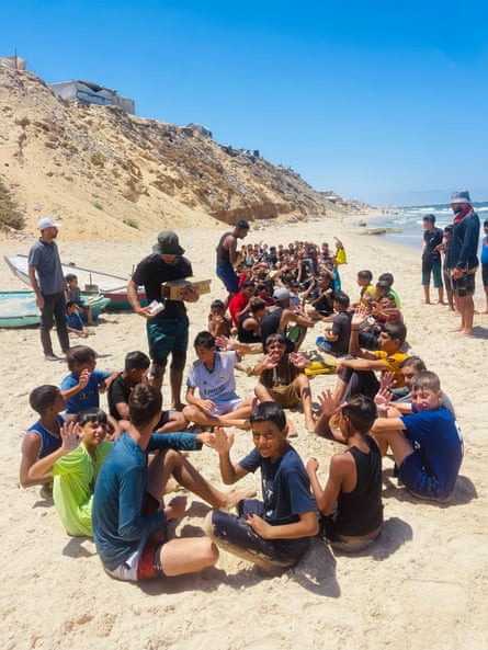 A group of children sitting on the beach after their swimming class