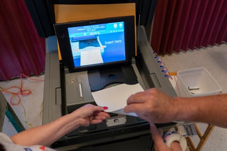 A polling judge, right, helps guide a voter’s ballot into a voting machine during the Pennsylvania primary election in 2022.Photograph: Carolyn Kaster/AP