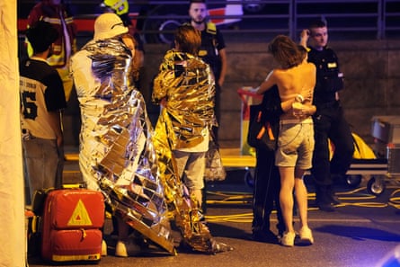 Two people embrace as they stand near emergency personnel in Berlin.Photograph: Markus Schreiber/AP
