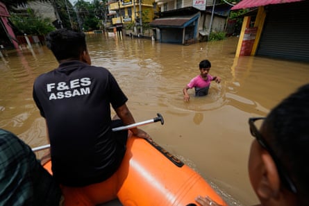 Rescue teams reach a man wading through flood water after heavy monsoon rain in Guwahati, India.Photograph: Anupam Nath/AP