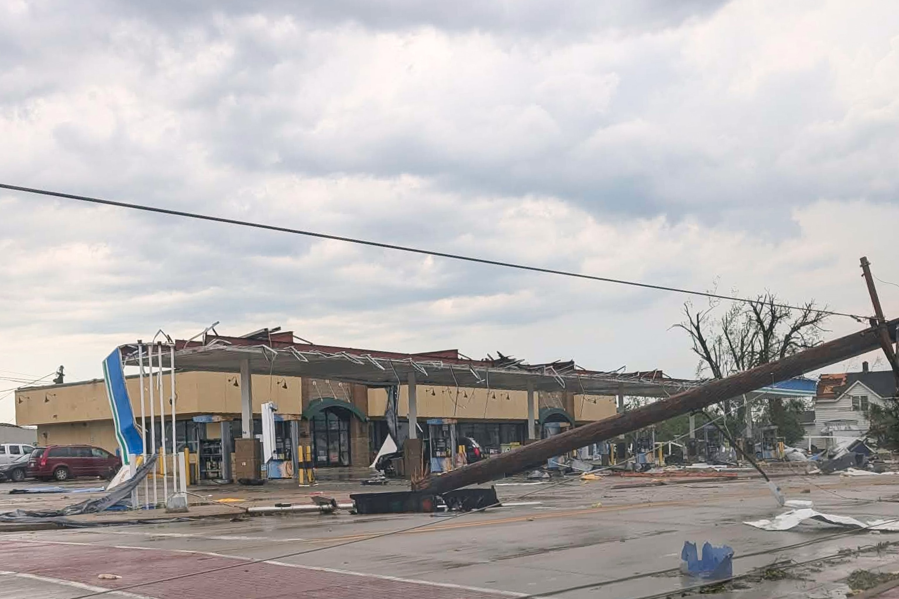 A telephone pole hangs above a road littered with debris from a severe storm in Menasha, Wis., July 27, 2026.Douglas Tom Williams via AP