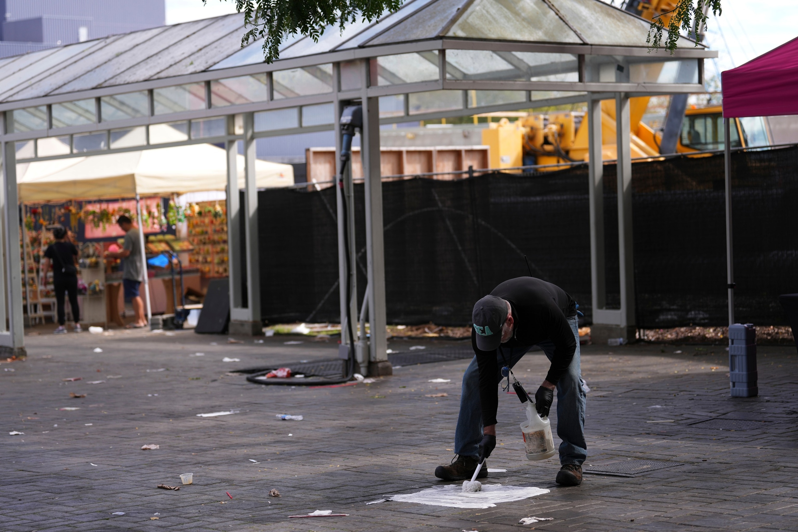 A worker cleans blood off the pavement the day after a shooting at Seattle Center during the Bite of Seattle food festival, July 27, 2026.Lindsey Wasson/AP Photo