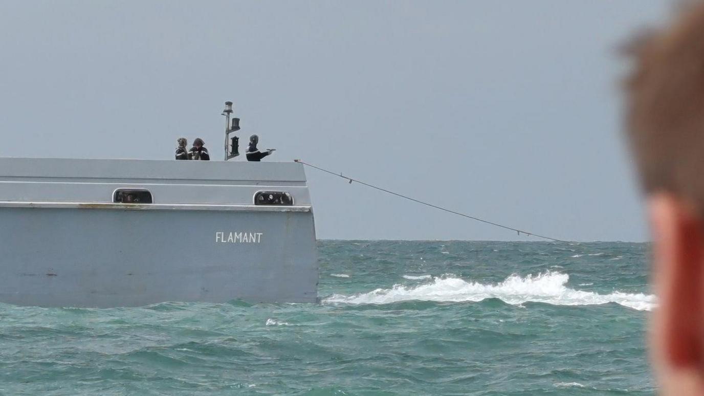 Image caption,A French patrol officer at the back of the boat was seen pointing a pistol towards the sea