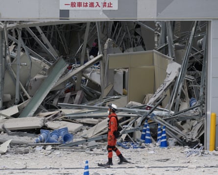 A rescue worker walks in front of the Aeon mall, which was damaged by an explosion after the earthquake.Photograph: Hiro Komae/AP