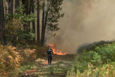 Two people look out at a landscape hit by wildfires in Crete, where authorities say two firefighters ‘fell heroically in the line of duty’.Photograph: ERT GR