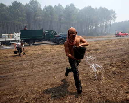 A volunteer carries a water bucket to help battling the fire in Lanton, west of Bordeau.Photograph: Romain Perrocheau/AFP/Getty Images