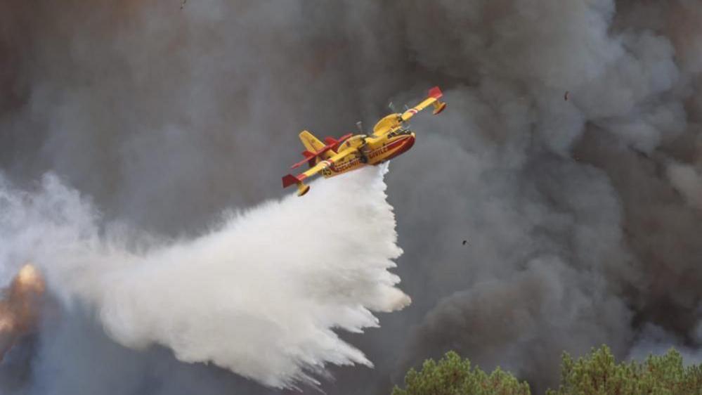 Image caption,A Canadair aircraft dropping water across a burning fire