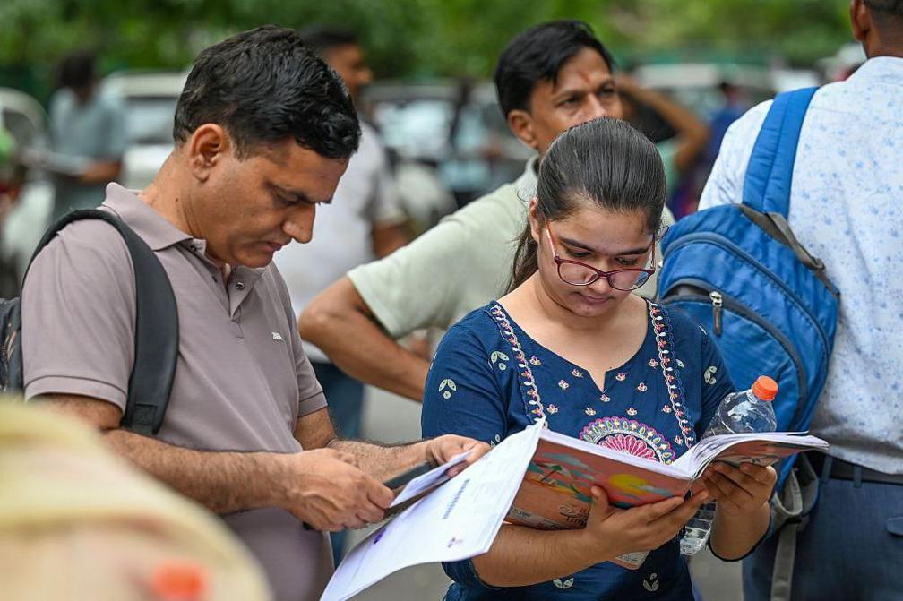 Image caption,A student arrives at a NEET centre in Delhi with her parent -  many study for months or years to prepare for the exam