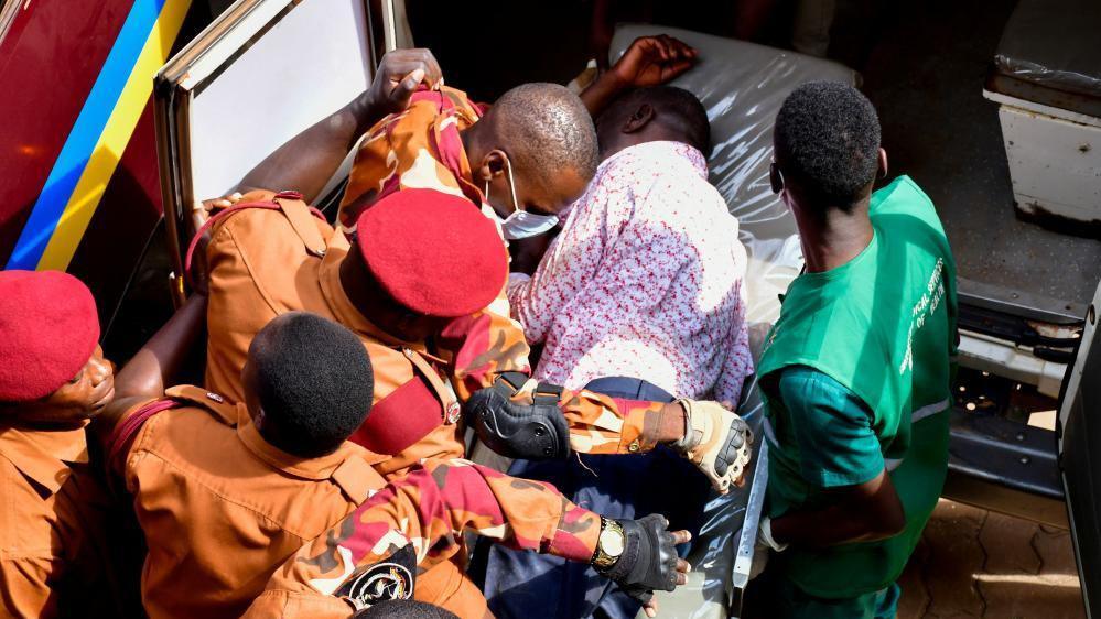 Image caption,Prison guards put Besigye in an ambulance after he collapsed