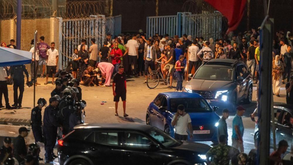 Image caption,People gather at the Bab Sebta border crossing between Morocco and the Spanish enclave of Ceuta, near Fnideq, Morocc