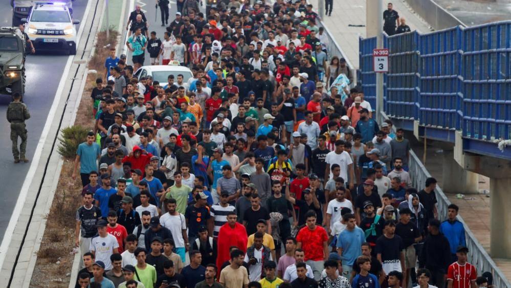 Image caption,Police have been escorting migrants off the Spanish territory on Saturday