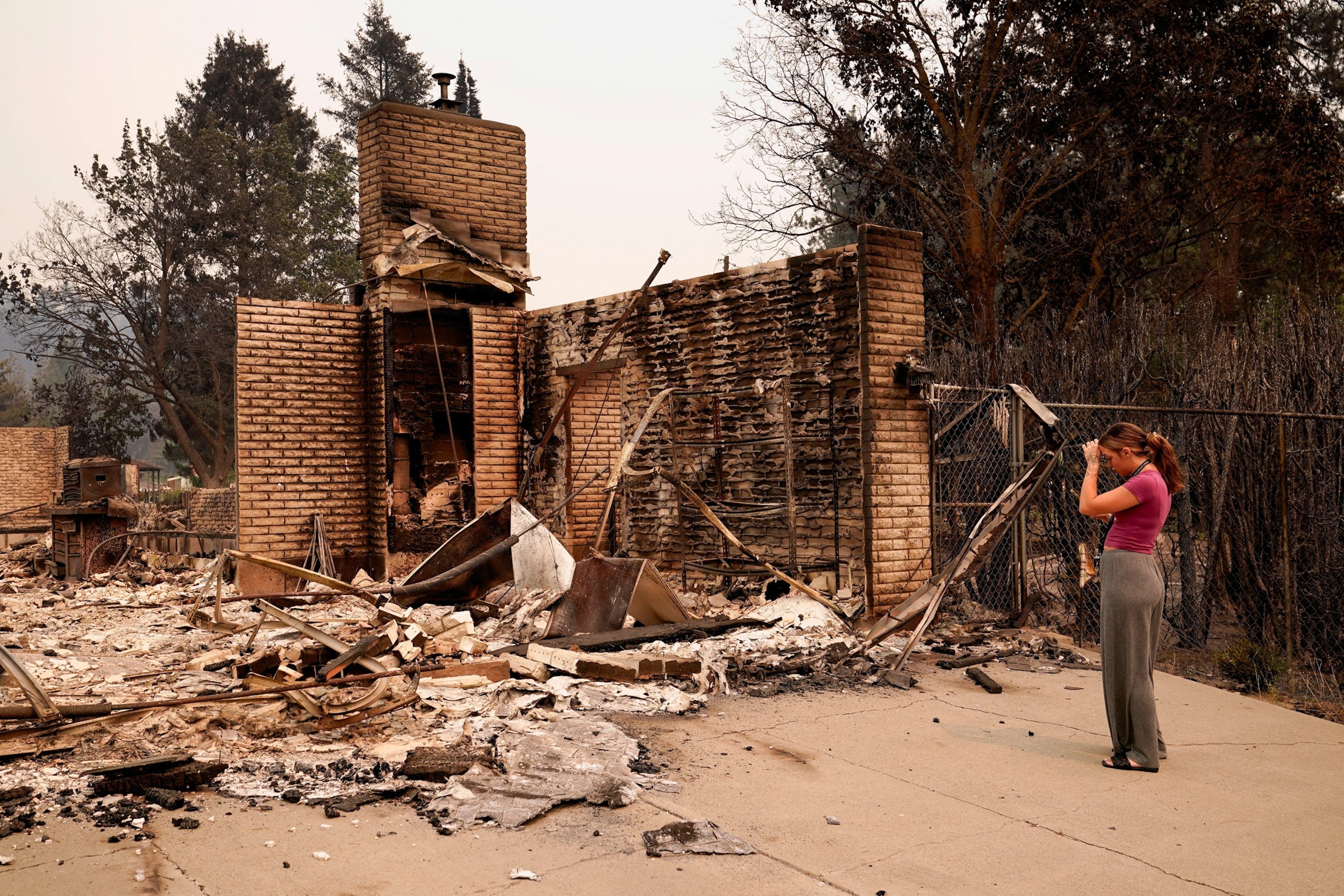 Ash Sollie stands in front of her grandparents' home, where she previously lived, after it was destroyed by a wildfire, in Spokane, Washington, U.S., August 2, 2026.David Ryder/Reuters