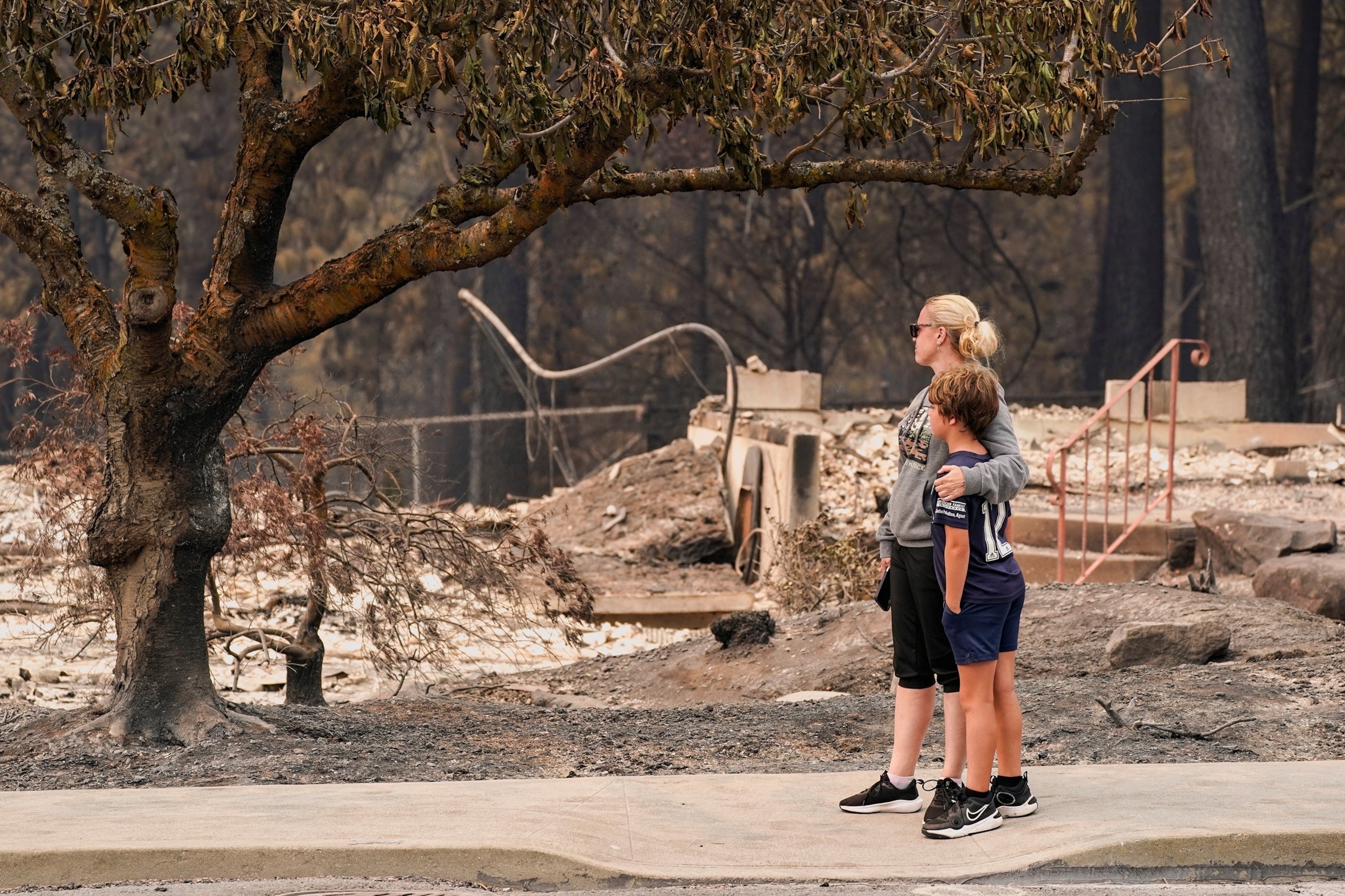 Jana Jensen surveys the neighborhood where her childhood home, owned by her parents, was lost to wildfire, while embracing her son, Aaren, 8, in Spokane, Washington, U.S., August 2, 2026.David Ryder/Reuters
