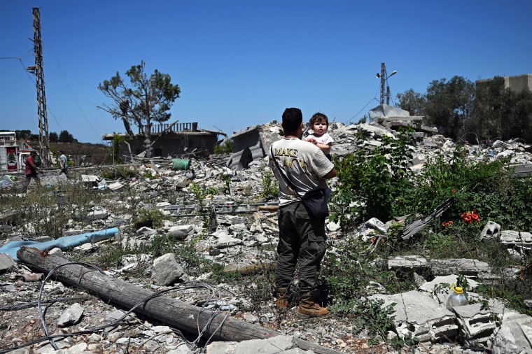 A man carries his niece on the rubble of his house in Zawtar al-Gharbiya, southern Lebanon, on July 28.Joseph Eid / AFP via Getty Images