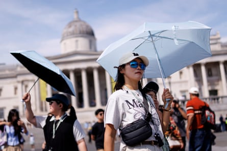People use umbrellas to shelter from the sun as they visit Trafalgar Square in central London.Photograph: Tolga Akmen/EPA
